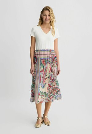 Kleid mit V-Ausschnitt, einer weißen Oberseite und einem fließenden, gemusterten Rock, der blumige und Paisley-Designs in Rosa-, Grün- und Blautönen aufweist.
