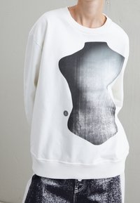 Vit sweatshirt med en stor, abstrakt svart och grå torso grafik. Mjuk textur med ribbade ärmslut och nederkant, designad för en avslappnad passform.