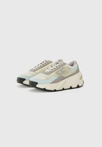 Sneaker mit einem hellblauen und beigen Obermaterial, das einen strukturierten grauen Wildleder-Akzent, weiße Schnürsenkel und eine dicke schwarze Sohle mit weißen Details aufweist.