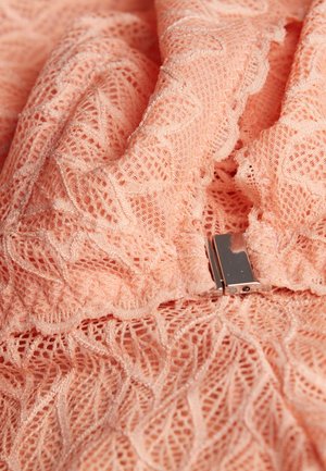 Tessuto in pizzo pesco con intricati motivi a foglia. Presenta una chiusura in argento, una consistenza morbida e un design a strati.