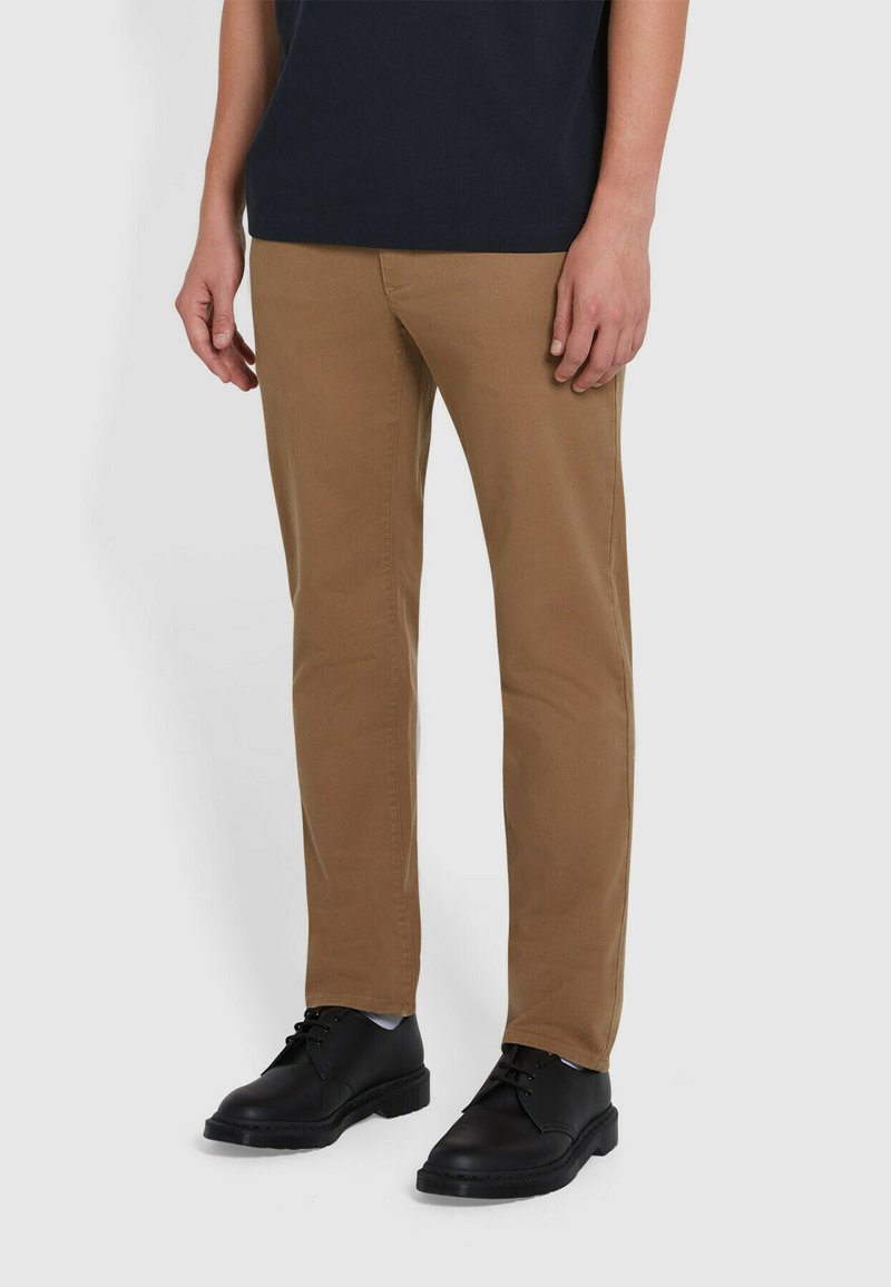 Pantaloni di cotone marrone a gamba dritta, abbinati a scarpe in pelle nere. Design semplice, senza motivi o accenti visibili.