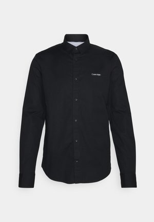 Schwarzes langärmliges Hemd mit Knöpfen, Kragen und kleinem weißen "Calvin Klein"-Logo auf der linken Brust.