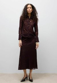 Burgundi pitsist top nööpkinnituse ja pikkade varrukatega, sobitatud pitsseelikuga, mõlemal lillemustriga. Mustad kontsakingad.