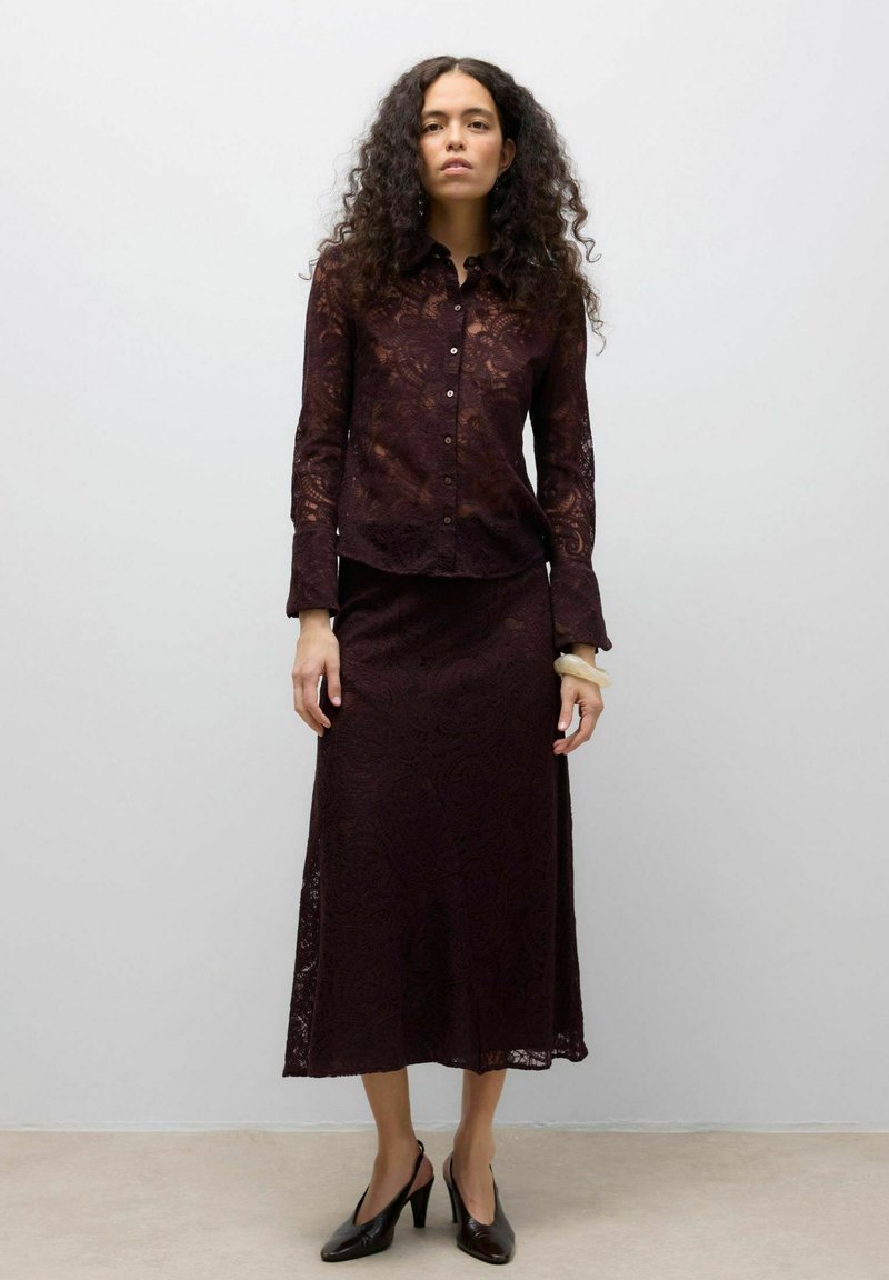 Burgundi pitsist top nööpkinnituse ja pikkade varrukatega, sobitatud pitsseelikuga, mõlemal lillemustriga. Mustad kontsakingad.