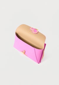 Ροζ δερμάτινο τσαντάκι χειρός με μπεζ εσωτερικό, κούμπωμα σε σχήμα καρδιάς σε χρυσό τόνο και χρυσή αλυσίδα ως λουρί σε λευκό φόντο.