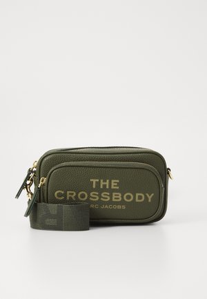 Green leather crossbody bag with two zippered compartments and gold lettering. Includes a fabric shoulder strap with a patterned accent.