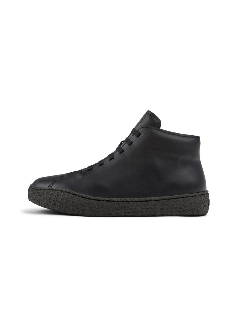 Zapato negro de cuero de caña alta con suela de goma negra texturizada, que presenta un diseño simple de cordones y una parte superior lisa y sin costuras.