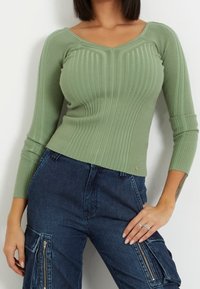 Helles grünes, geripptes Strickoberteil mit V-Ausschnitt und langen Ärmeln. Verfügt über eine figurbetonte Passform und ein kleines Logodetail am Saum.