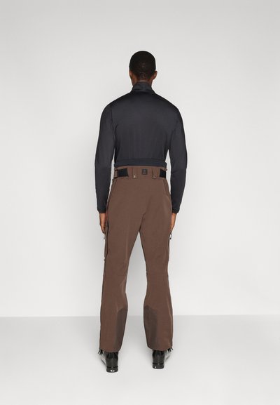 Meeste suusariietus, mis koosneb keha järgnevast mustast pika varrukaga toppist ja pruunidest suusapükstest lukuga, tugevdustega põlvedel ja reguleeritava vööga.