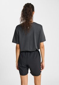 Svarta träningsshorts med elastisk midja, ihop med en mörkgrå t-shirt med kort ärm som har en liten logotyp på ryggen.