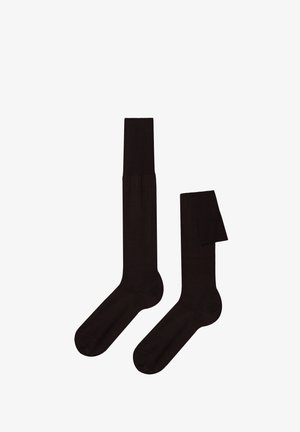 Schwarze Socken aus glattem, elastischem Material. Mit einem gerippten Bündchen und einer nahtlosen Zehenpartie. Eine Socke ist teilweise gefaltet.