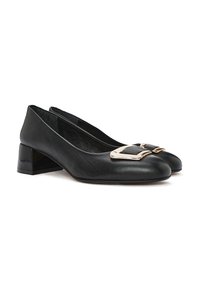 Scarpe con tacco a blocco in pelle nera, dotate di punta arrotondata e un grande cinturino metallizzato decorativo sulla parte superiore. Texture liscia con design elegante.