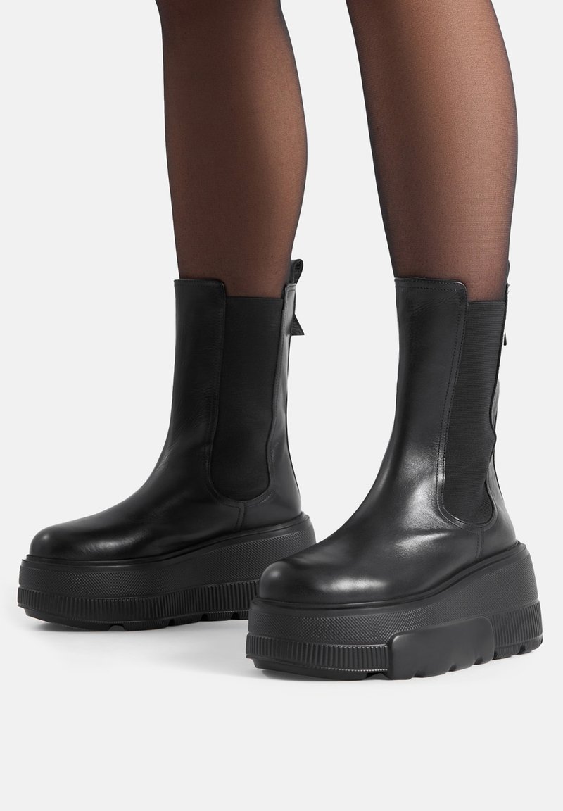 Czarne skórzane botki na kostkę z grubą podeszwą na platformie i elastycznymi panelami po bokach dla łatwego zakładania. Gładka faktura i minimalistyczny design.