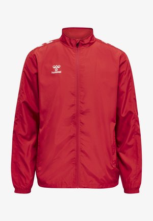 Rote Windjacke aus leichtem, glänzendem Stoff. Verfügt über einen hohen Kragen, einen Reißverschluss und elastische Bündchen. Inklusive weißem Logo auf der Brust.