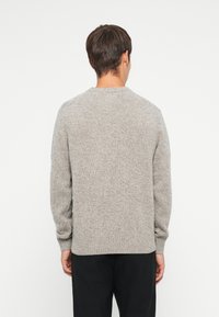 Gray knitted sweater with long sleeves, crew neckline, and ribbed cuffs and hem. Textured fabric with a soft appearance.