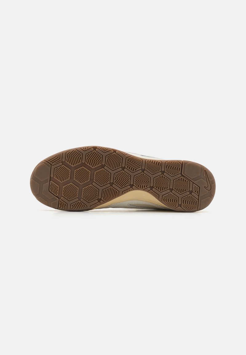 Suela de zapato deportivo de goma con un patrón hexagonal, de color marrón claro y superficie texturizada para tracción. Diseño de tacón ligeramente elevado.