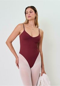 Bordo kopalke z nastavljivimi spaghetti naramnicami in kontrastnim svetlo roza visokim pasom. Gladek material z oprijetim silhueto.