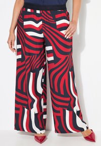 Red, white, and navy striped wide-leg pants with a flowing fabric texture and an elastic waistband, featuring a bold graphic pattern.