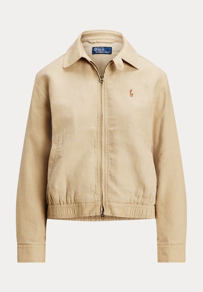 Beige lettvektsjakke med glidelås foran, krage, elastiske mansjetter og nederkant, med en liten brodert logo på venstre bryst.