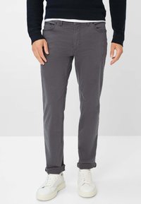 Pantaloni in cotone grigi con vestibilità slim, caratterizzati da orli arrotolati, tasche frontali e un design pulito, abbinati a sneaker bianche.