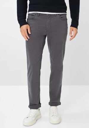 Graue Baumwollhosen mit slim Fit, mit umgeschlagenen Säumen, Fronttaschen und einem schlichten Design, kombiniert mit weißen Sneakern.