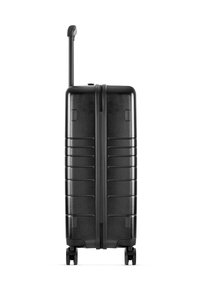 Zwarte harde koffer met verticale ribbels, een telescopische handgreep en vier soepel draaiende wielen. Heeft een centrale ritssluiting.