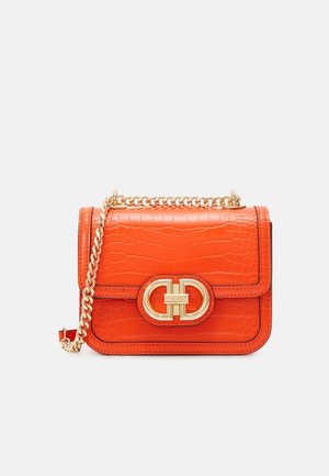 Mała pomarańczowa torebka ze skóry o fakturze krokodyla, z złotym łańcuszkiem na ramię i złotym logo na przednim klapie.