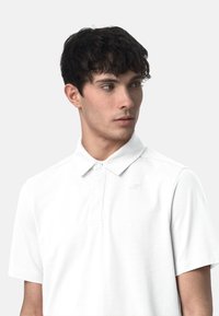 Polo shirt bianco con colletto, caratterizzato da un logo discreto sul petto. Realizzato in tessuto liscio, ha maniche corte e una vestibilità classica.
