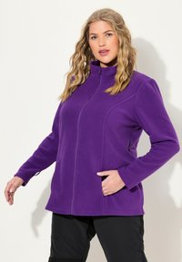 Giacca in pile viola con colletto alto, chiusura con zip anteriore e tasche laterali. Caratterizzata da maniche lunghe e una texture liscia e morbida.