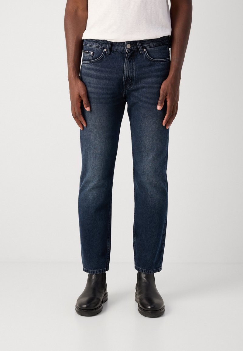 Granatowe dżinsy o prostym kroju, z pięcioma kieszeniami, z zapięciem na guzik i zamek błyskawiczny oraz delikatnym wyblaknięciem na udach.