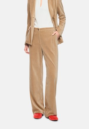 Beige velvet wide-leg pants paired with a matching blazer, white blouse, and bright red fuzzy flat shoes.