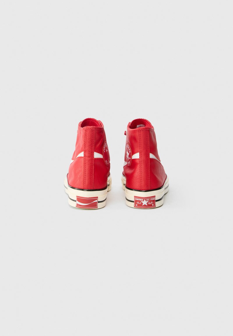 Sneaker alte rosse in pelle liscia con accenti bianchi, sole in gomma e dettagli del logo sul tallone e sul lato.