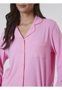 Camisón de rayas rosa con mangas largas, cierre de botones, un bolsillo en el pecho y ribete amarillo en contraste en el cuello y el bolsillo.