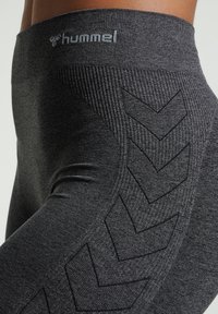 Szare legginsy sportowe z teksturowanym pasem i kontrastowym wzorem w zygzak wzdłuż boku. Wykonane z elastycznej dzianiny.