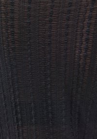 Sort stof med teksturerede lodrette striber og små, rundede mønstre. Materialet virker let og en smule gennemsigtigt.