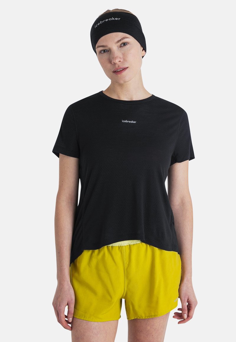 Camisa negra de manga corta con el logo de Icebreaker, combinada con pantalones cortos amarillos. Textura suave, corte relajado y diseño de cuello redondo.