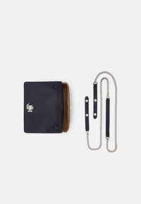 Bolsa de cuero azul marino con superficie texturizada y logo plateado, con un interior beige y correa de cadena desmontable. Incluye correas adicionales de cuero.