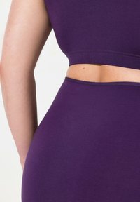 Fioletowy dopasowany crop top i wysoko taliowane spodenki wykonane z miękkiego, elastycznego materiału. Posiadają bezszwowy design i gładką teksturę.
