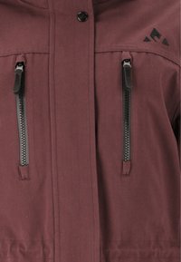 Bordeauxjack met een soepele textuur, voorzien van twee ritszakken met zwarte hardware en een subtiele logo op de rechterbovenkant.