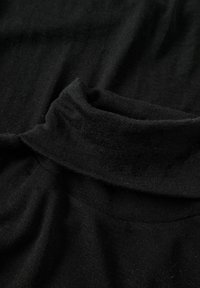 Maglione nero a collo alto realizzato in morbido tessuto testurizzato. Presenta un colletto arrotolato e un materiale liscio e cadente con una leggera lucentezza.