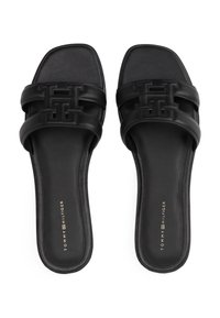 Schwarze Rutschsandalen mit zwei breiten Riemen, die ein geometrisches Logodesign zeigen. Glatte Ledertextur und quadratische Zehenform.