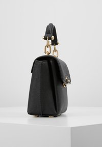 Borsa nera con una forma strutturata, texture sintetica liscia, dettagli in metallo dorato e manico superiore con attacco a catena.