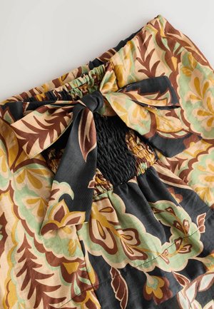 Daudzkrāsaina ziedu auduma blūze ar melnu smockēta auduma daļu un loku detaļu viduklī. Teksturēts un viegls audums.