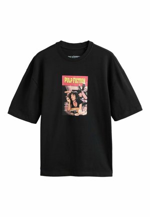 Sort oversized T-shirt med motiv af en kvinde, der ligger ned og ryger, med teksten "PULP FICTION" i gult på en rød baggrund over hende.