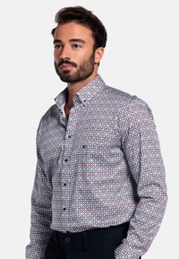 Overhemd met knopen, voorzien van een geometrisch patroon in blauw, rood en wit. Gemaakt van katoen met een gestructureerde kraag en lange mouwen.