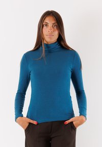 Maglioncino blu realizzato in un tessuto a maglia morbido, con maniche lunghe e una silhouette aderente, abbinato a pantaloni marrone scuro.