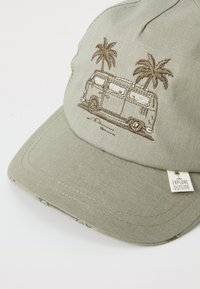 Helle grüne Kappe mit gesticktem Vintage-Bus und Palmen. Aus Baumwollmaterial, gebogenem Visier und einem "Explore Outside"-Label an der Seite.