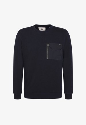 Tumši zila jakas ar noapaļotu dekoltē, garām piedurknēm un krūšu kabatu, kurai ir rāvējslēdzēja aizdare un teksturēts audums.