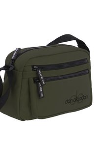 Bolso cruzado de color verde oliva con dos bolsillos frontales con cremallera, correa ajustable y herrajes negros. Presenta una textura suave y detalle de logo.