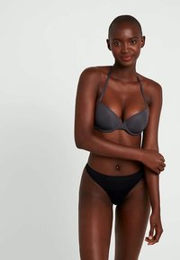 Szary stanik z wyściółką i cienkimi ramiączkami, zestawiony z czarnymi majtkami typu bikini o wysokim kroju. Oba elementy charakteryzują się gładką fakturą i prostym wzornictwem.